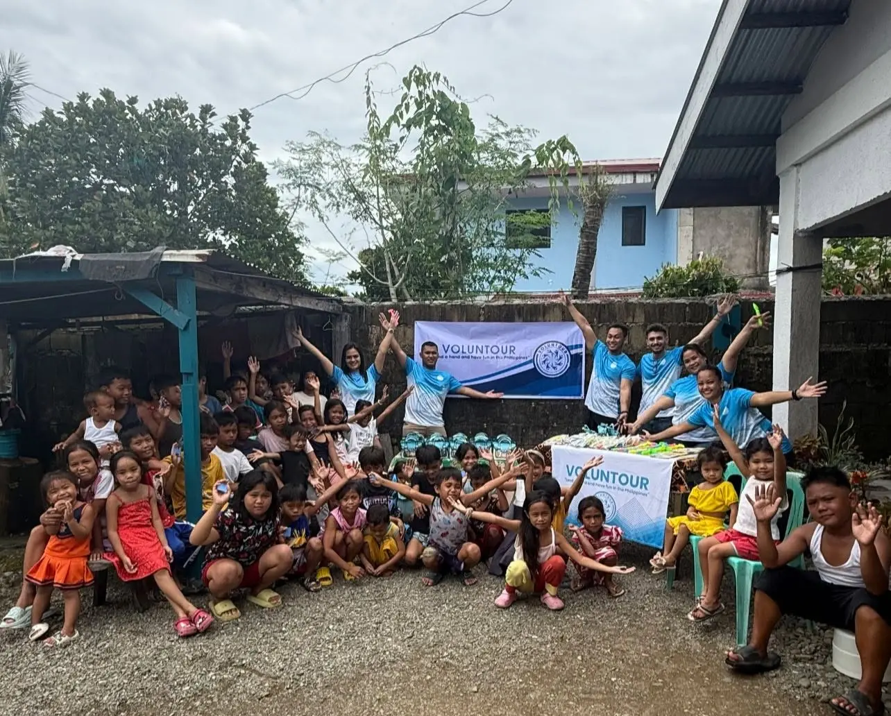 Large group of children and adults gathered in front of a building during a Voluntour Philippines outreach event in Dingalan, Aurora.