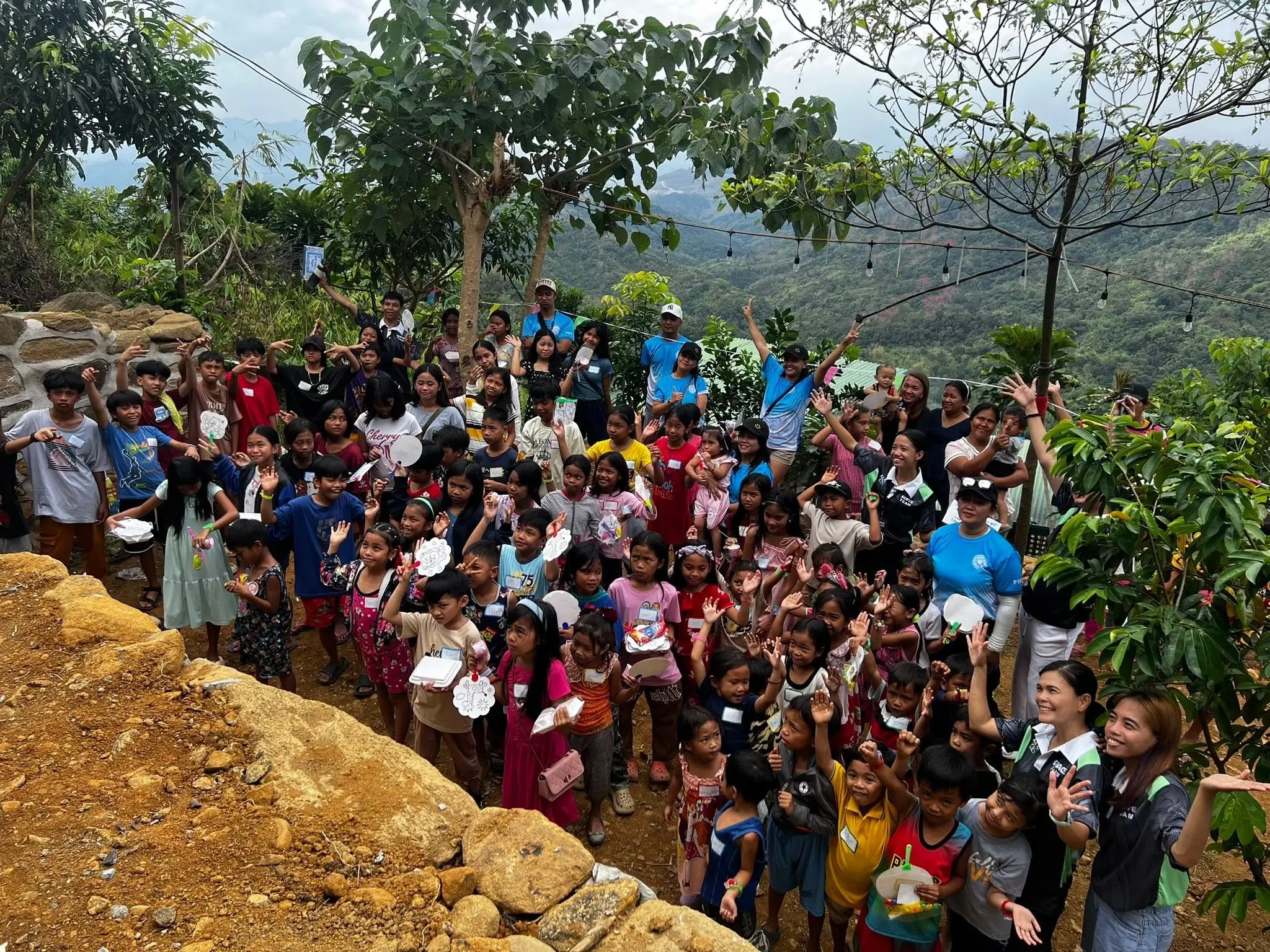 Large group of volunteers gathered on a hillside at Mt. Balagbag, surrounded by trees and natural scenery.