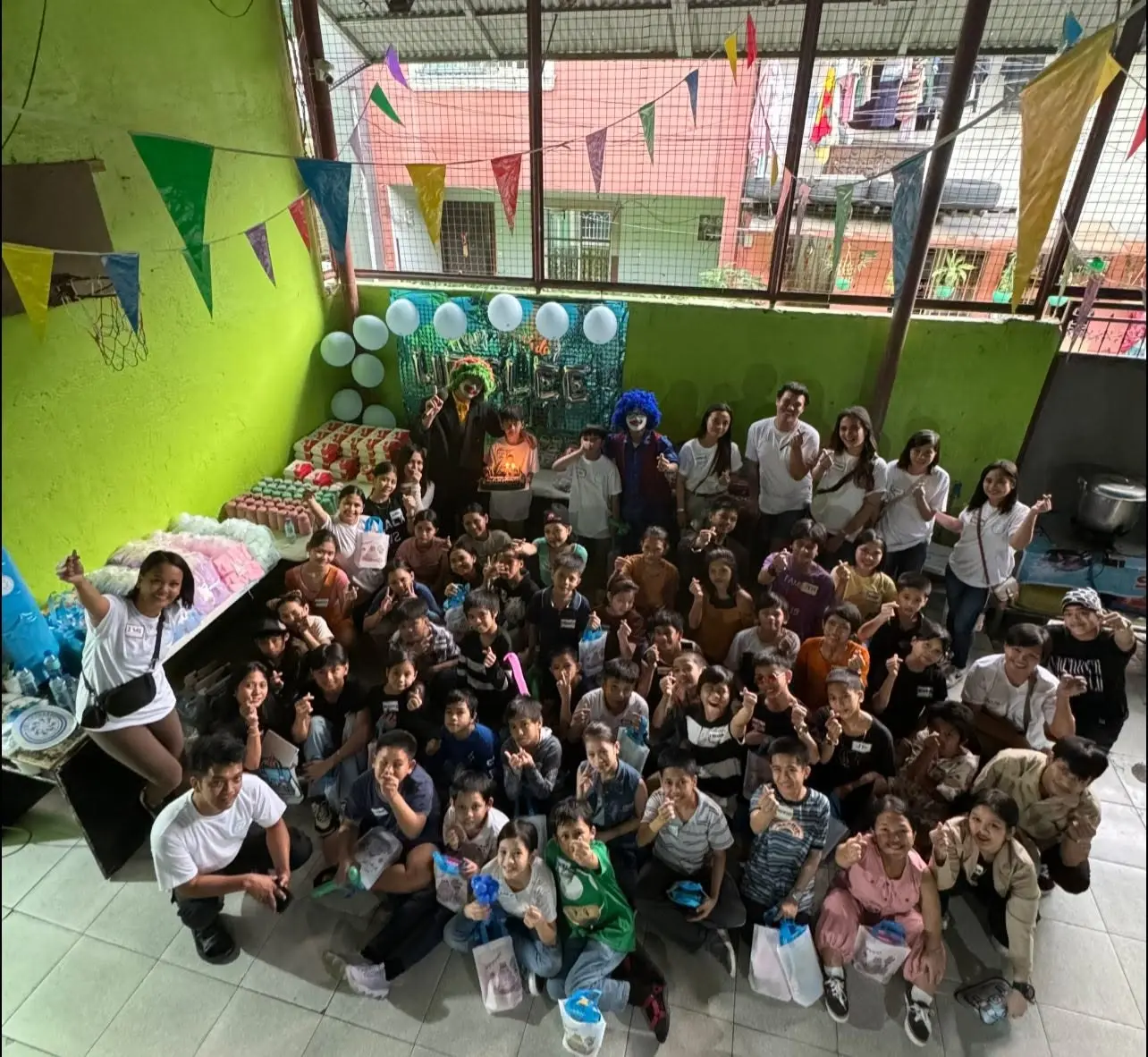 Community members and volunteers seated indoors in a bright green room decorated with banners and posters during the Oplan Shelter program.