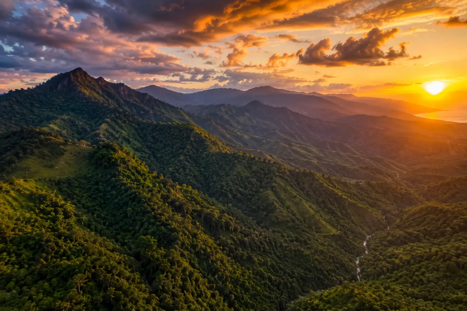 Wide drone shot of Philippine mountains and dense forests under dramatic evening skies.